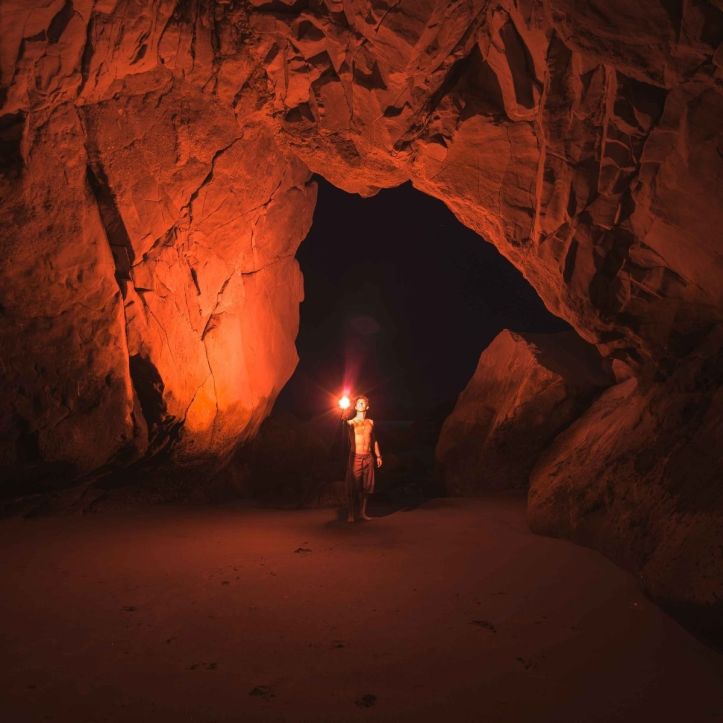 A path in a cave illuminated by the soft light of a torch, symbolizing a Christian haiku on trusting God in difficult times."