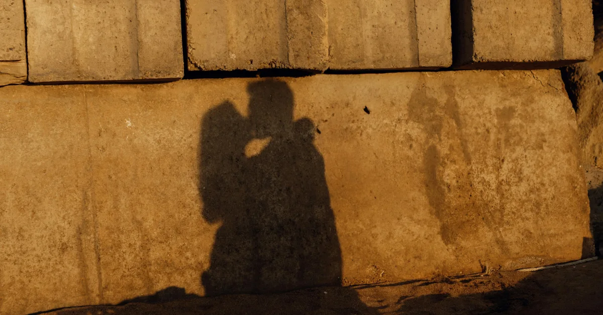 silhouette of a man and woman kissing on a stone wall