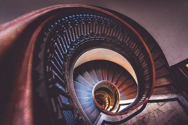 Spiral staircase curling downward inside a historic building.